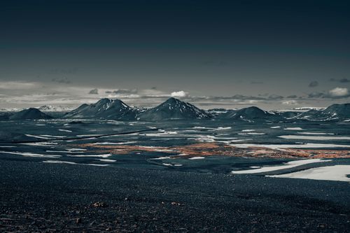 Free Stunning Icelandic mountain landscape with rugged terrain and snow patches under a cloudy sky. Stock Photo