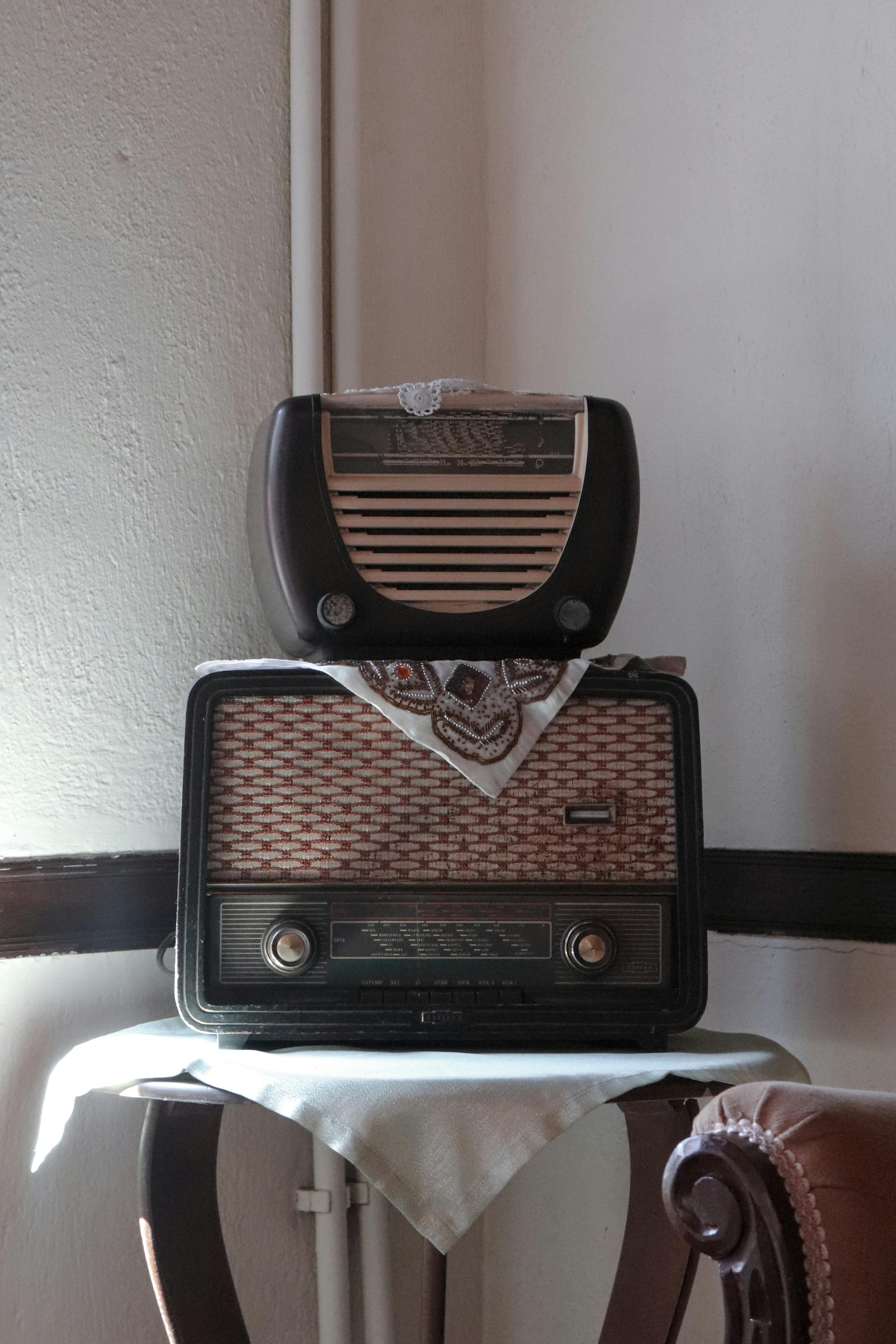 Gratis Et par retro-radioer stablet på et trebord med en vintageduk, som fanger nostalgisk sjarm. Arkivbilde