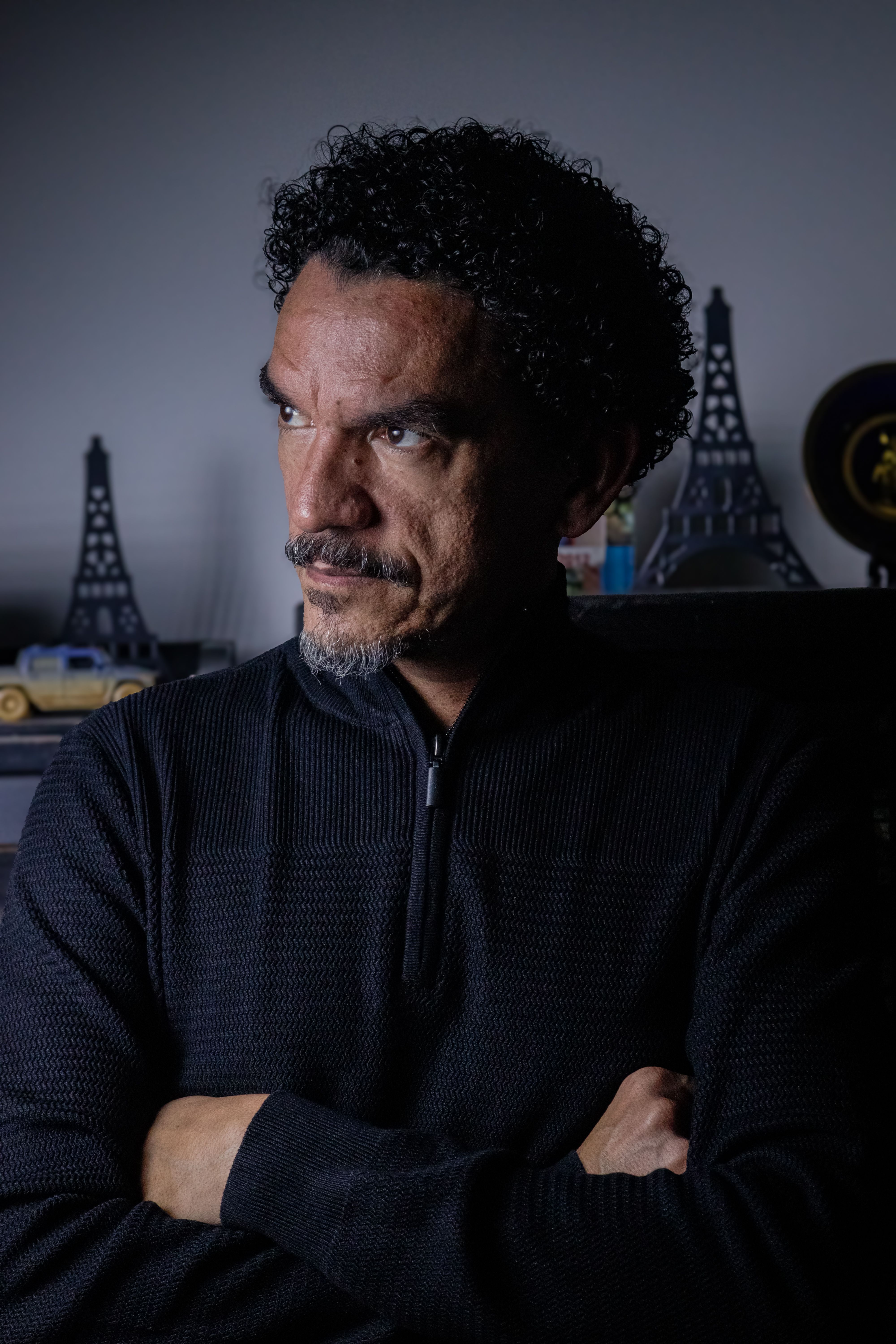 A thoughtful man in a dark setting with Eiffel Tower models, highlighting a Parisian ambiance.