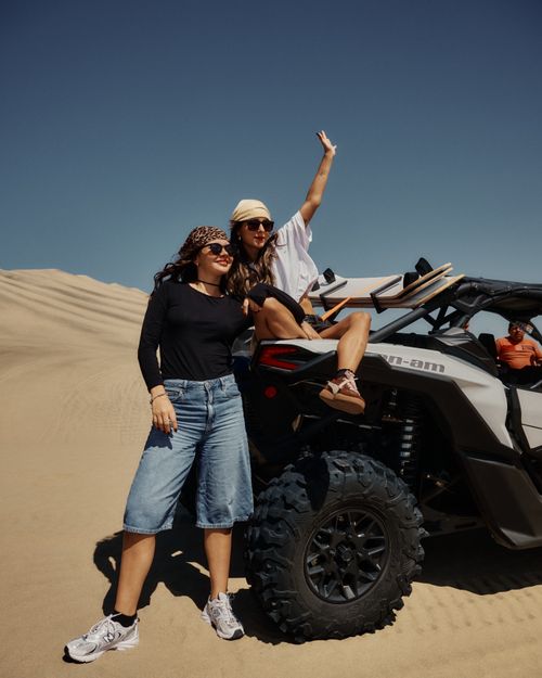 Free Two women pose with an ATV in a desert landscape, enjoying a sunny outdoor adventure. Stock Photo