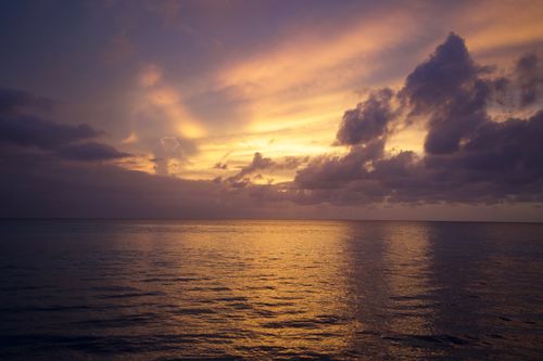 Free Captivating sunset over calm ocean waters with dramatic cloud formations. Stock Photo