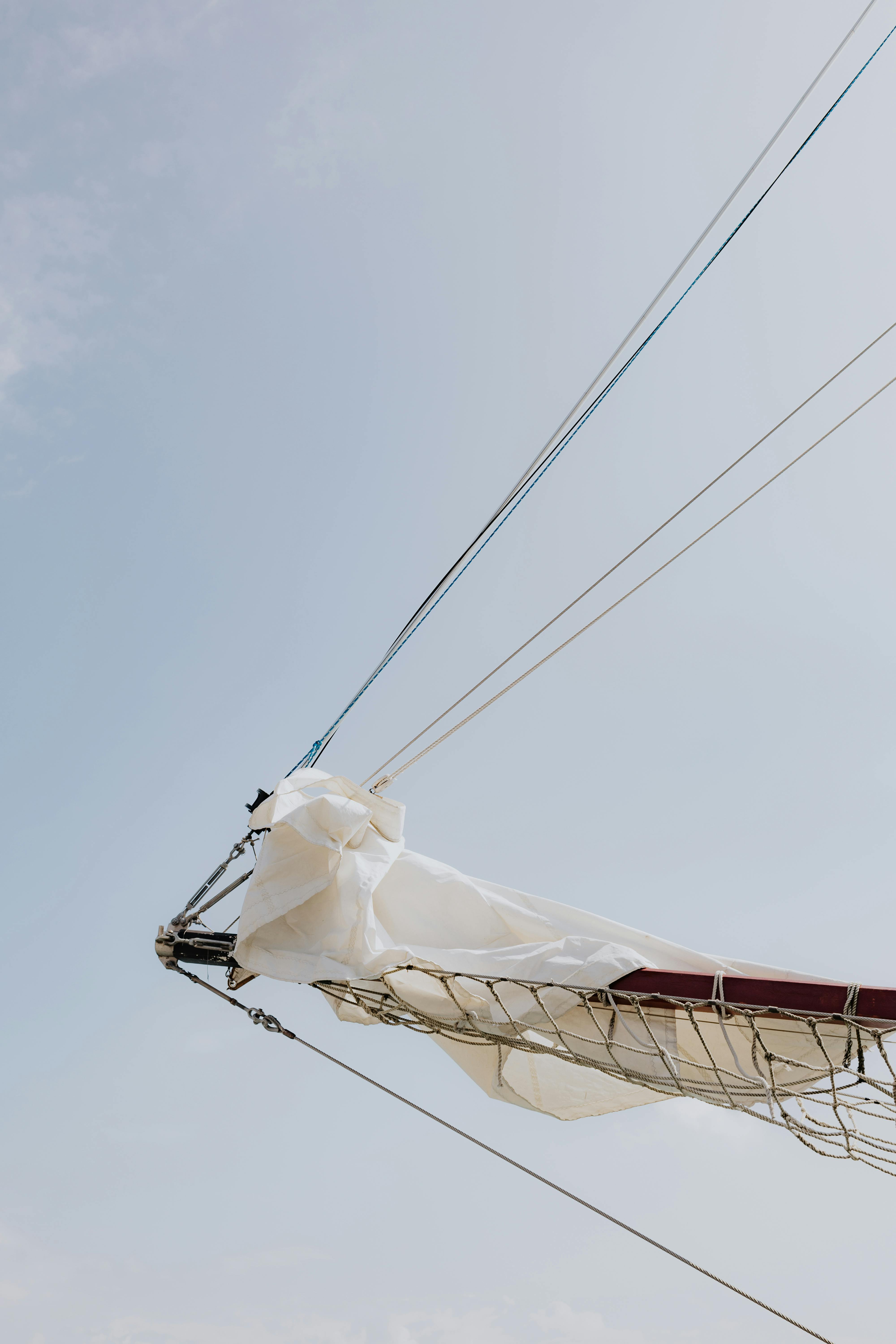 A sailboat's mast and boom with sails in Chicago's open sky.