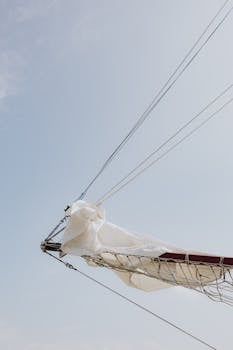 A sailboat's mast and boom with sails in Chicago's open sky.