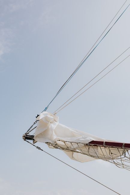 A sailboat's mast and boom with sails in Chicago's open sky.