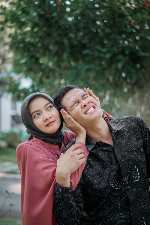 Free A joyful couple shares a playful moment in a sunny outdoor setting, surrounded by nature. Stock Photo