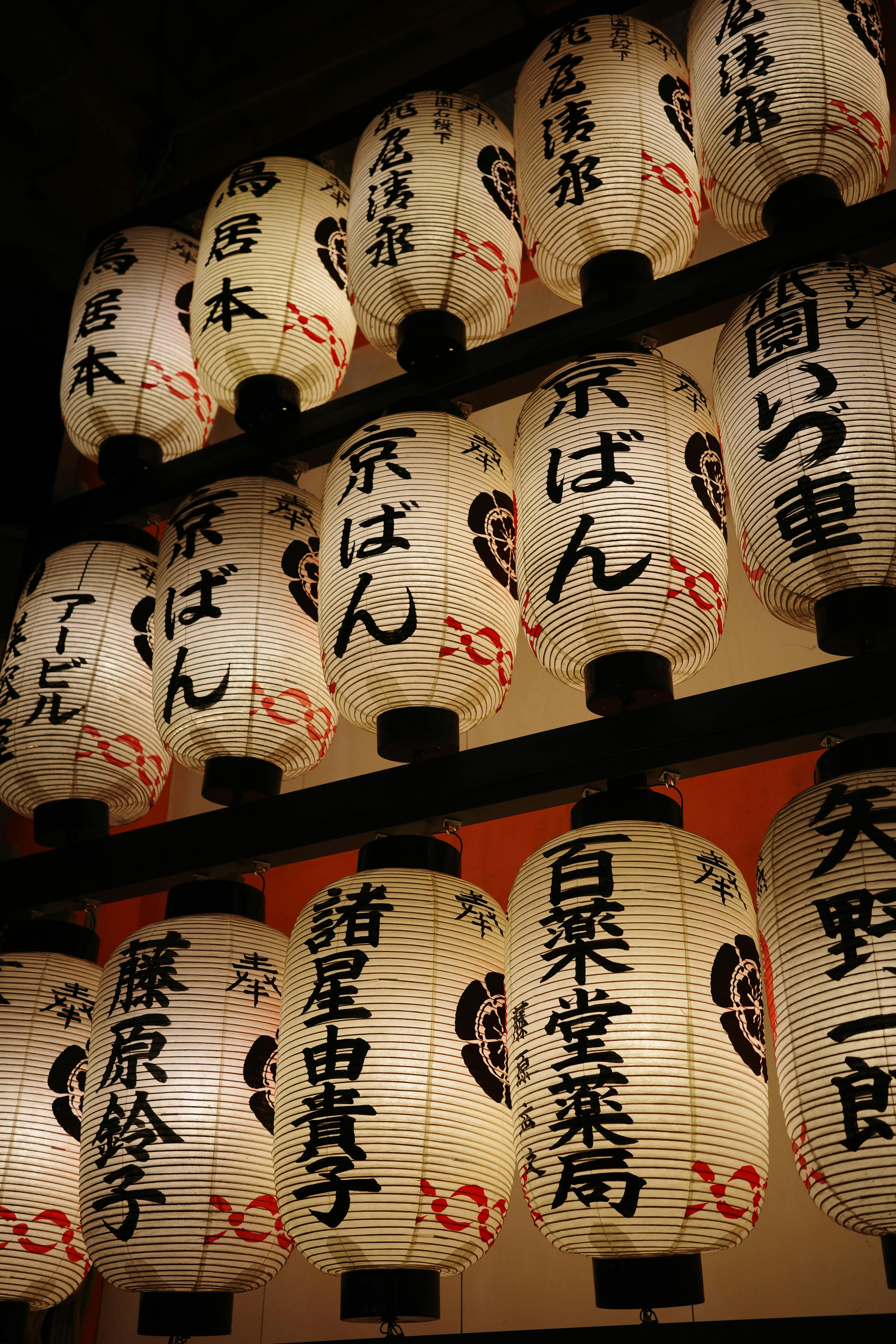 Paper lanterns with Kanji symbols illuminated during a nighttime festival in Japan.