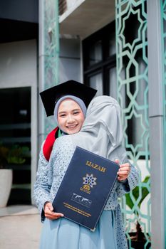 Graduates in hijabs celebrate outdoors with diploma certificate, symbolizing achievement and joy. - Fotografer Sidoarjo
