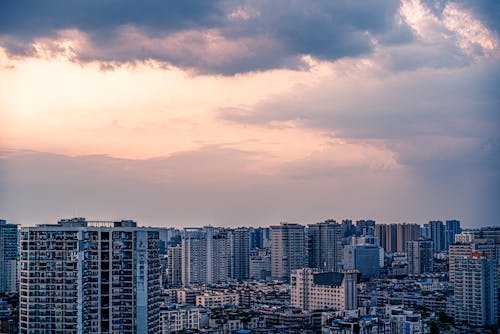 City Skyline Under Orange and Gray Cloudy Sky during Sunset