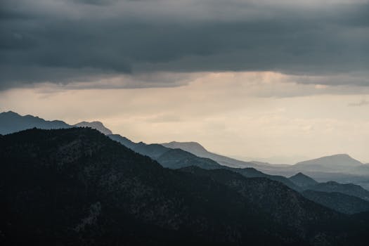 Majestic mountains under a dramatic sky, showcasing moody clouds and scenic vistas.