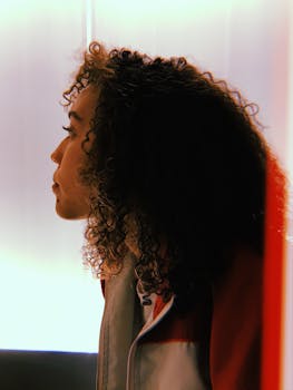 在柔和的灯光下，一位卷发女性的侧面轮廓被以怀旧的风格捕捉