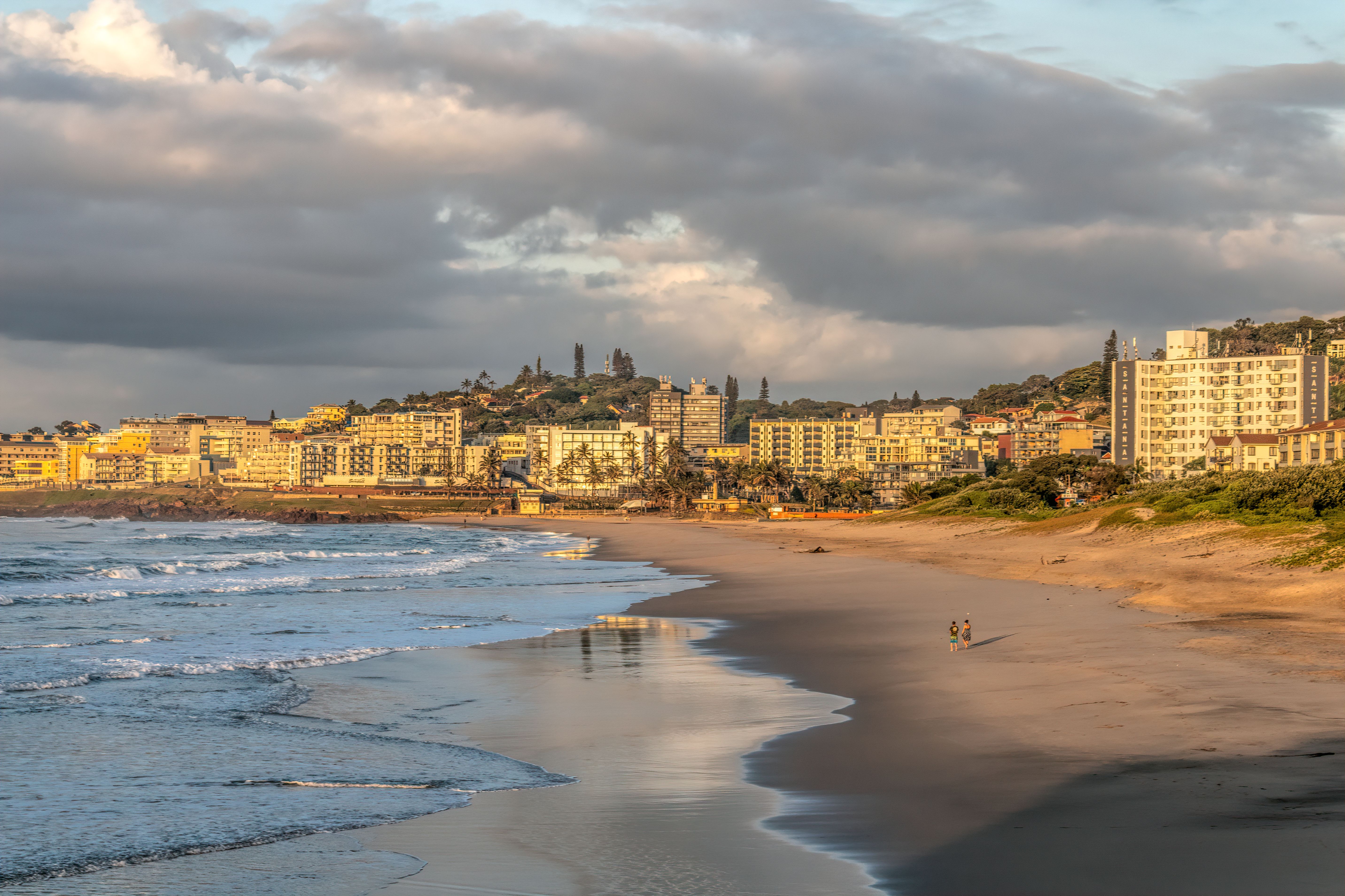Stunning view of Margate Beach, South Africa during sunset, showcasing buildings and the ocean shore.
