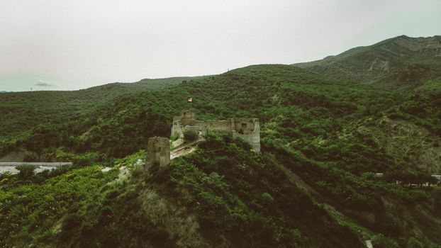 Discover the ancient Georgian castle nestled in lush green hills, offering a serene and historic landscape.