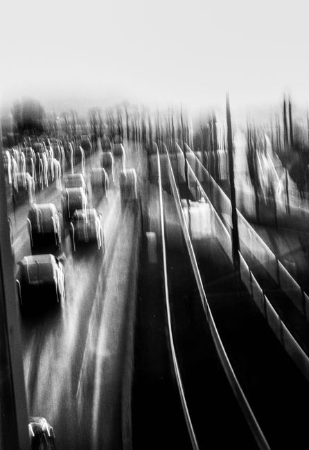 Blurry black and white image of highway traffic showcasing vehicles in motion and abstract light trails.