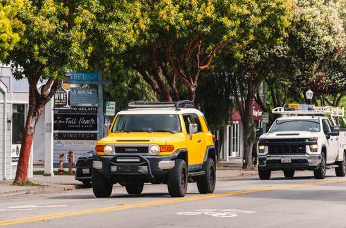 Free A yellow Toyota SUV driving through a vibrant street in Half Moon Bay, California. Stock Photo