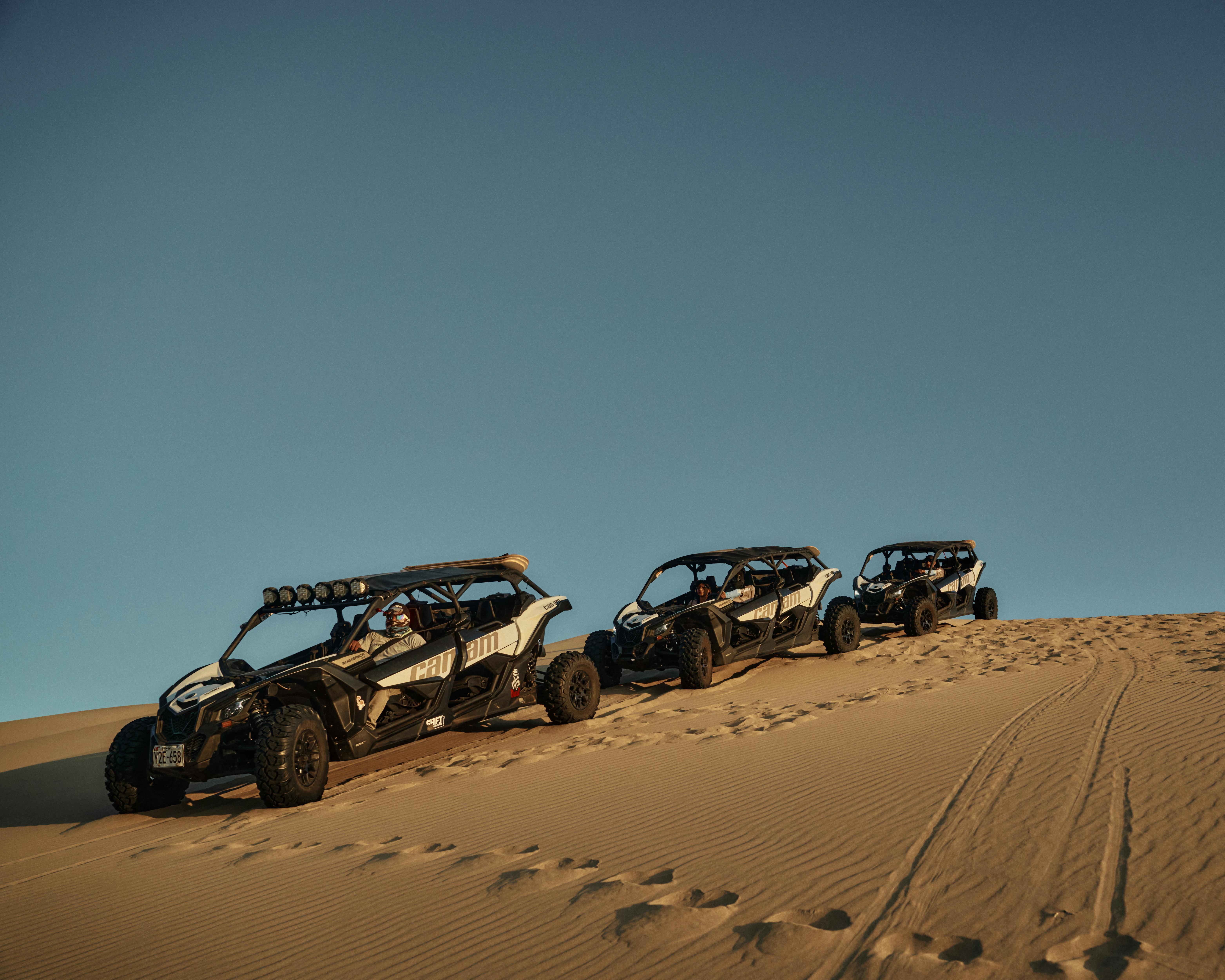 Three ATVs traverse desert dunes during a stunning sunrise, showcasing adventure and exploration.
