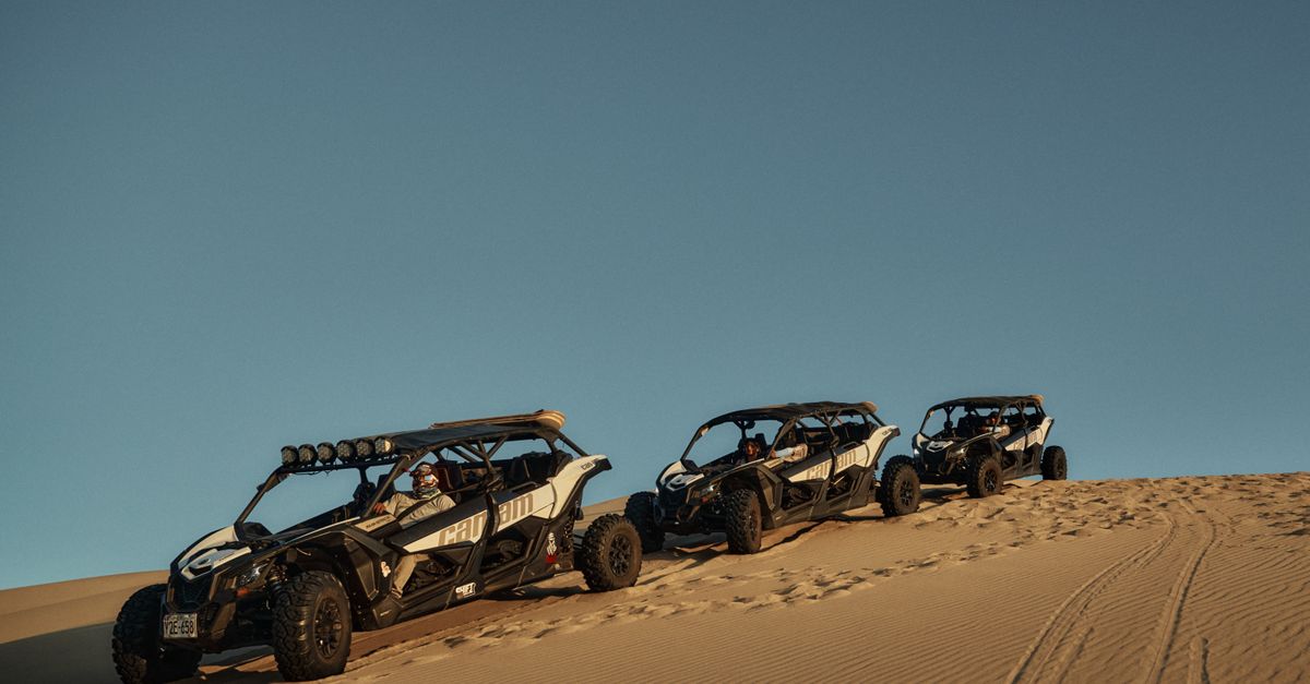 Three ATVs traverse desert dunes during a stunning sunrise, showcasing adventure and exploration.