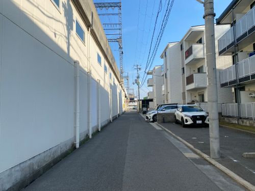 Free Quiet urban alleyway with residential buildings and parked cars under a clear blue sky in Japan. Stock Photo