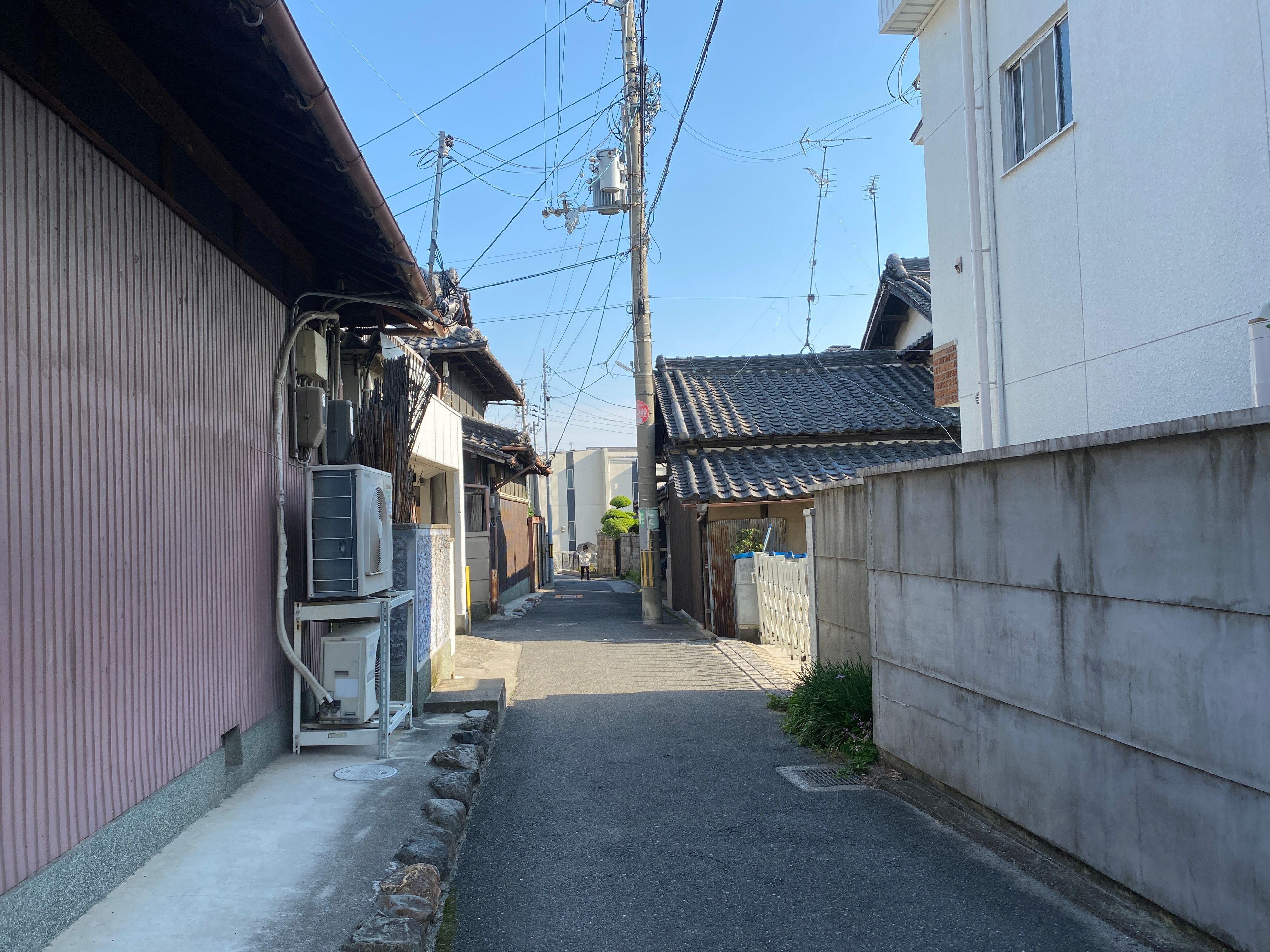 古い瓦屋根の家が並ぶ住宅街の細い道