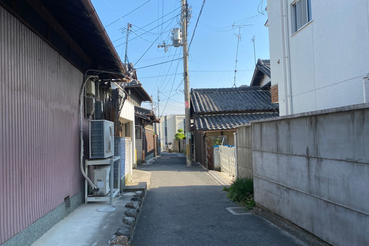 古い瓦屋根の家が並ぶ住宅街の細い道