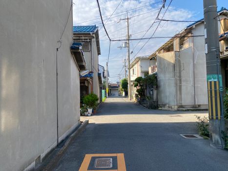 Serene view of a narrow residential street in Osaka during daytime, showcasing traditional architecture.