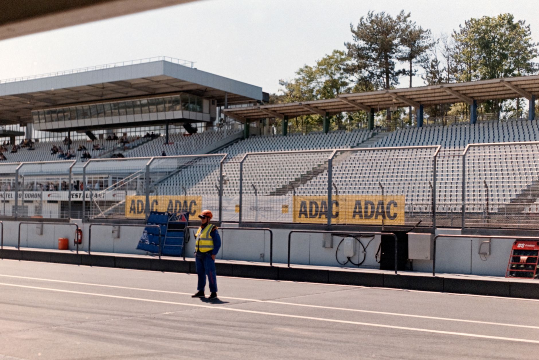 Spacious racing track with grandstand view, featuring a lone security guard. Ideal for motorsport ev