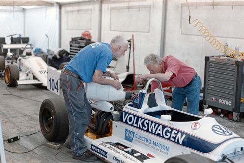 Free Two senior mechanics servicing race cars in a workshop garage. Stock Photo