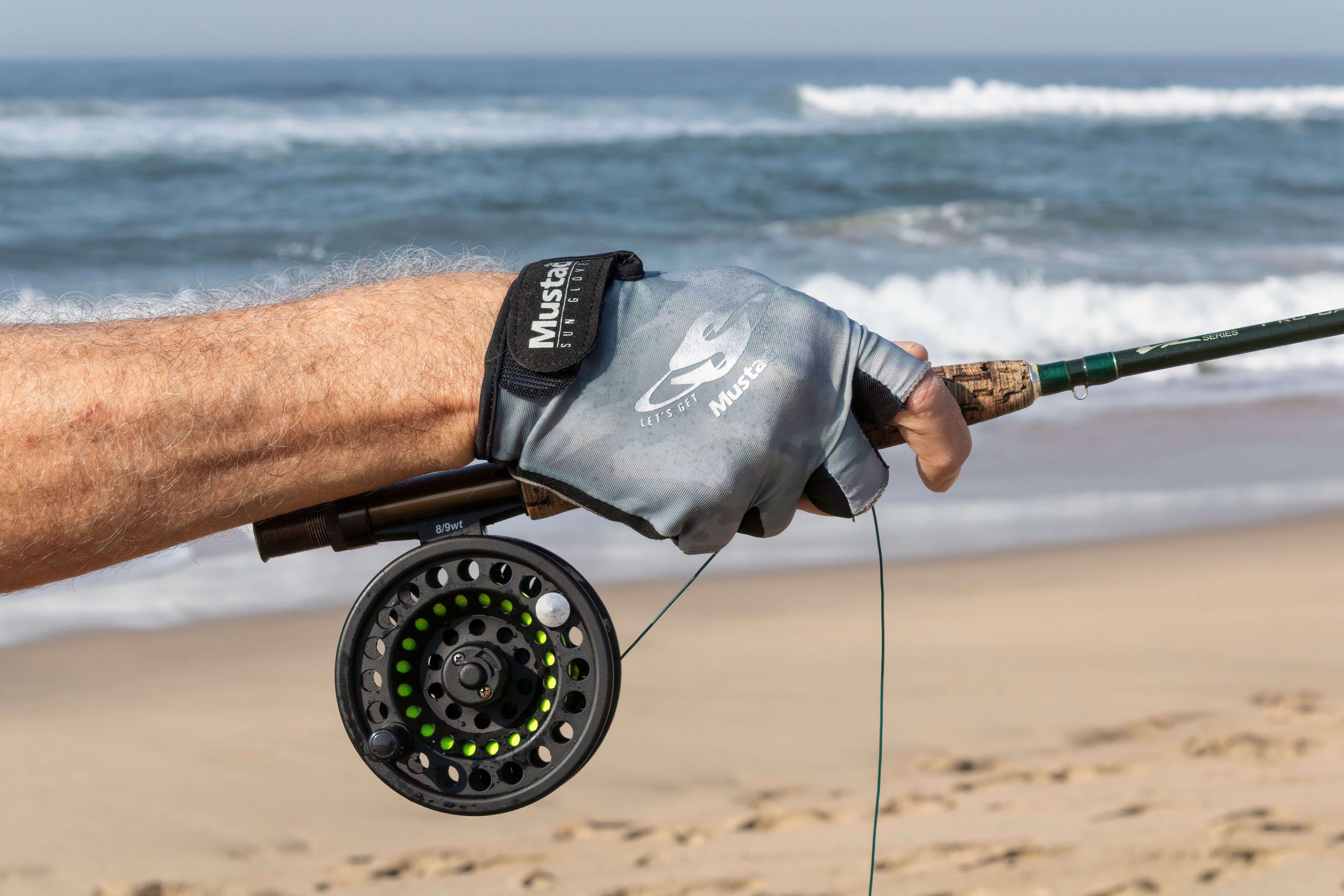 Close-up of a fly fishing rod and gloved hand on Margate Beach, South Africa.