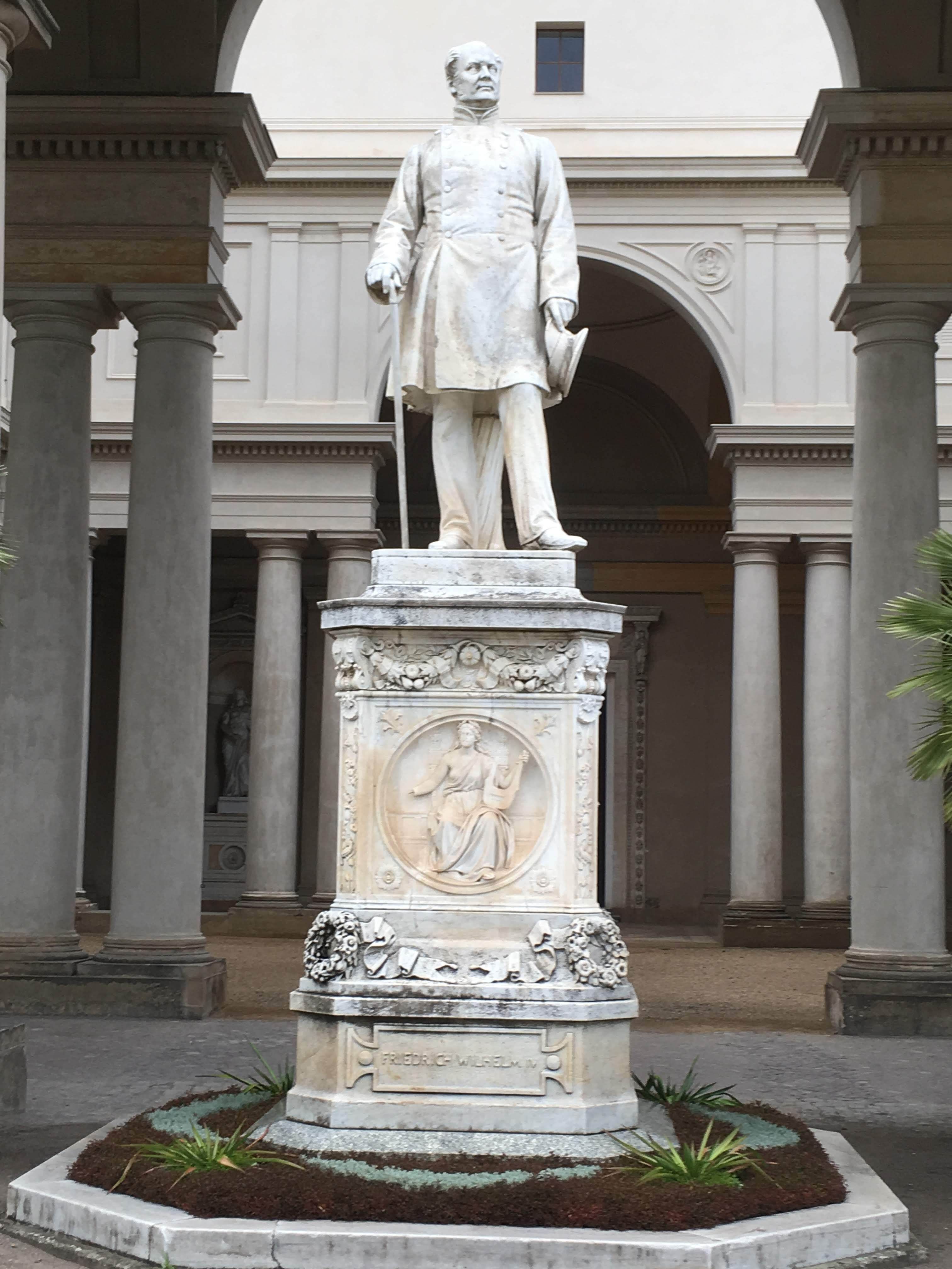 Marble statue of a historical figure in Berlin's classic architecture.