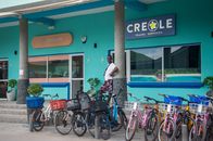 Man stands among bicycles outside a vibrant travel service office, showcasing lively urban life.