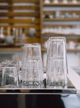 A close-up of stacked clear glasses on a reflective surface in a modern indoor setting.