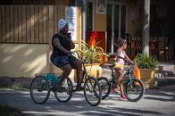 Two people enjoy a leisurely bike ride in a sunny urban setting, highlighting community and leisure.