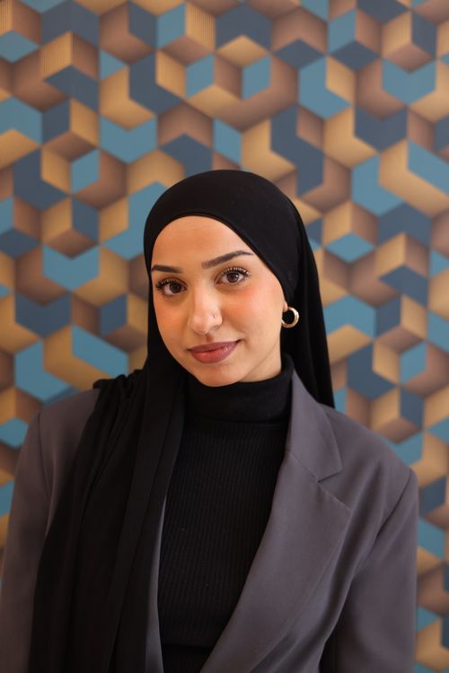 Free Elegant portrait of a woman wearing a hijab against a colorful geometric background. Stock Photo