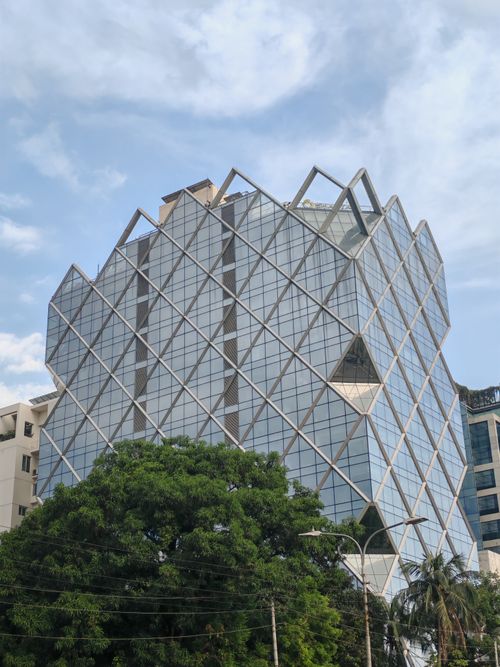 Free A striking geometric glass building with tree-lined streets, showcasing modern architecture. Stock Photo