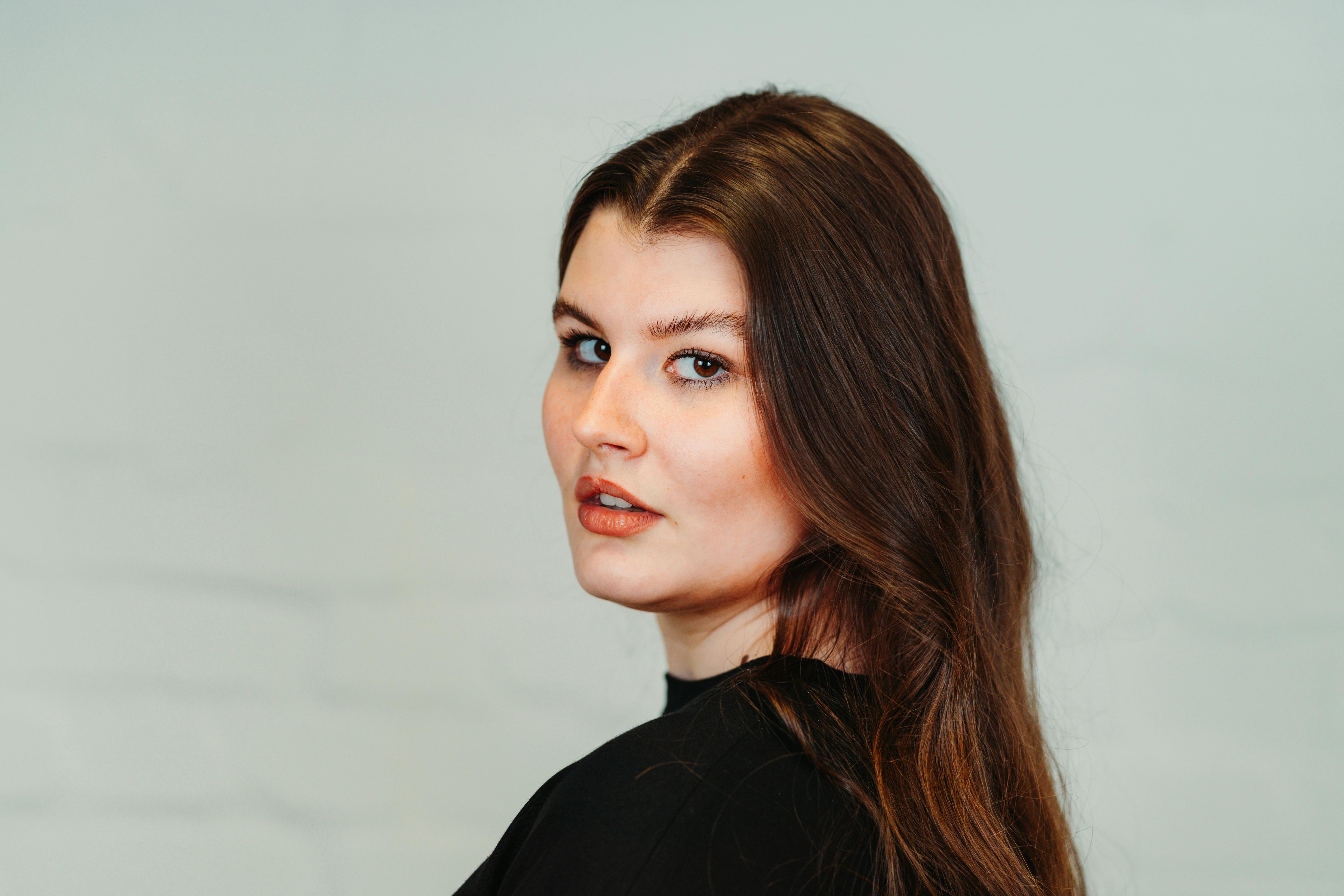 Gratis Fængslende portræt af en brunette kvinde i et moderne studiemiljø, der udstråler elegance og ynde. Lagerfoto