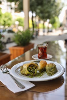 A plate of assorted Turkish baklava with a cup of tea served outdoors in Gaziantep, Turkey.