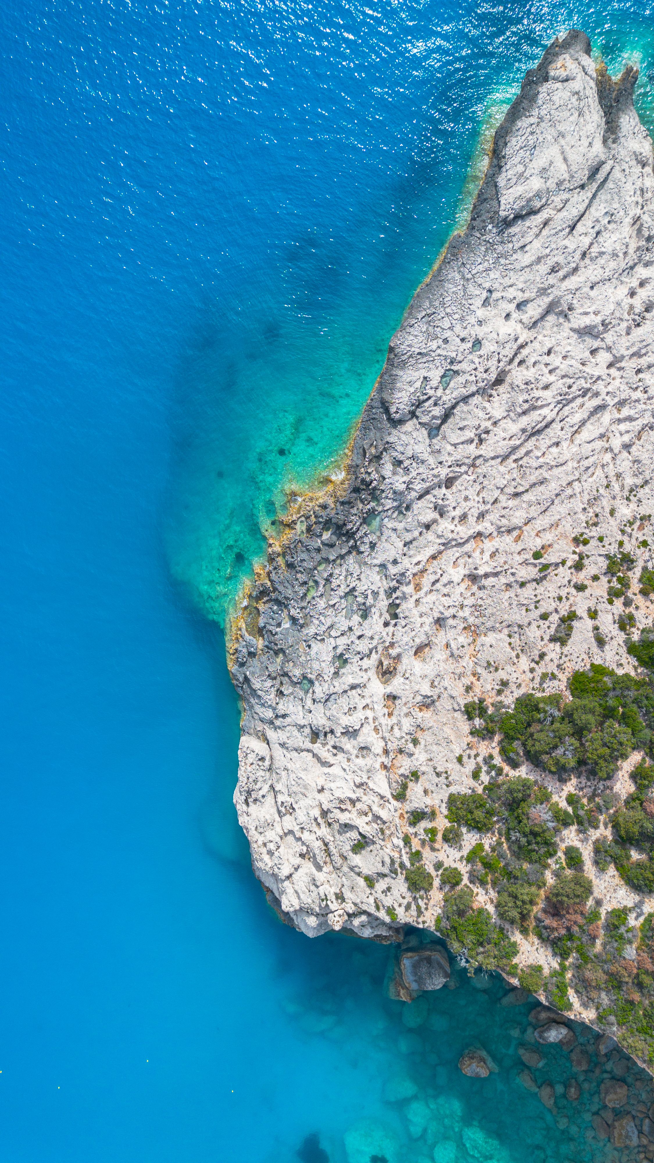 Aerial View of Rocky Coastline with Blue Water · Free Stock Photo