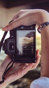 Close-up of a person holding a camera capturing a scenic view through the viewfinder.