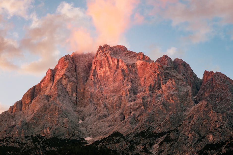 A breathtaking view of a rugged mountain peak during sunset with vibrant clouds.