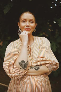 Stylish woman with tattoos wearing a striped dress outdoors, reflecting a blend of fashion and personal expression.
