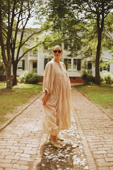 Pregnant woman in striped dress walks gracefully on a brick path in North Carolina.