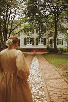 Elegant woman in vintage dress walking towards a historic house in North Carolina