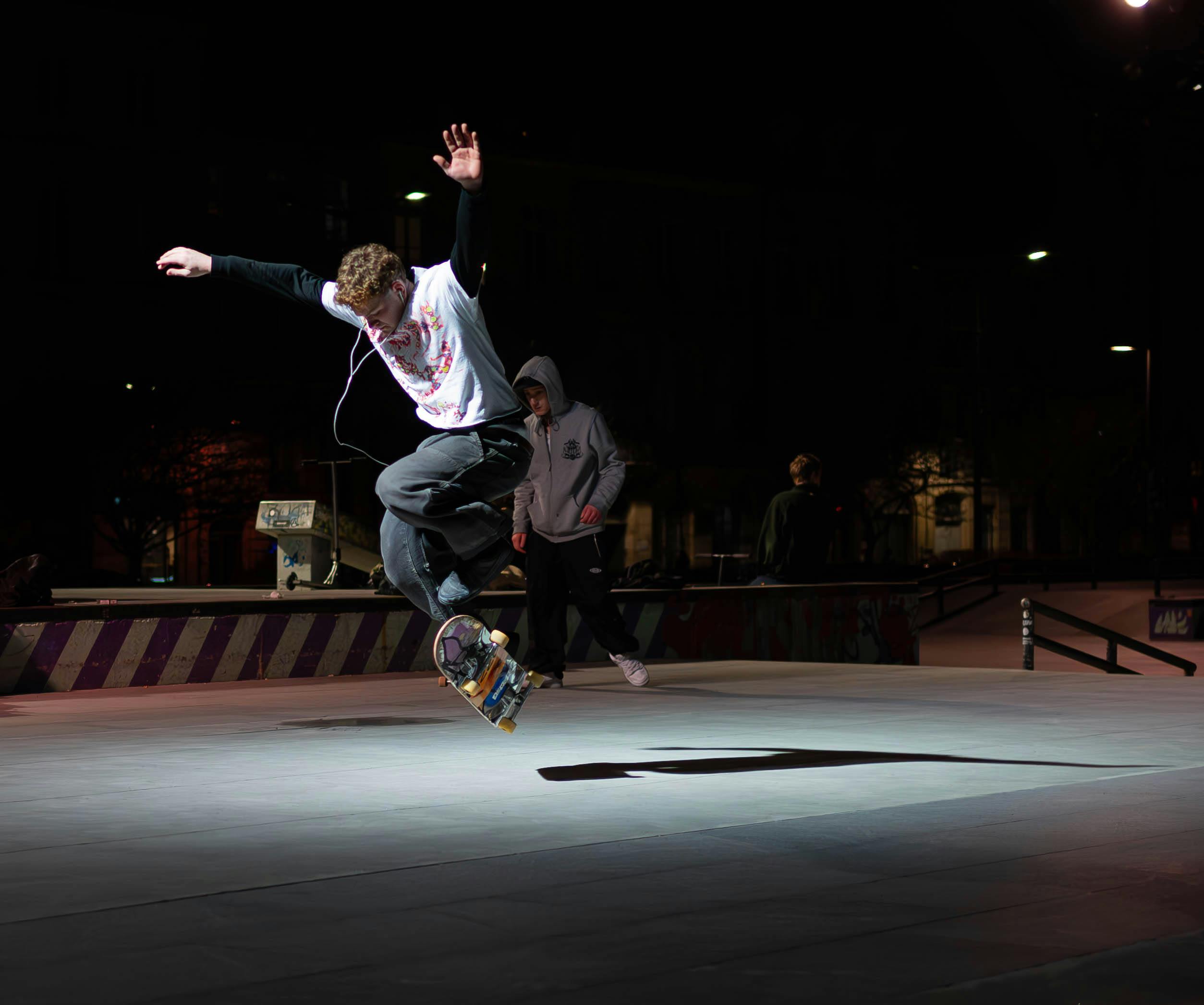 Skateboarder performing tricks under lights at a park in Bordeaux, France.