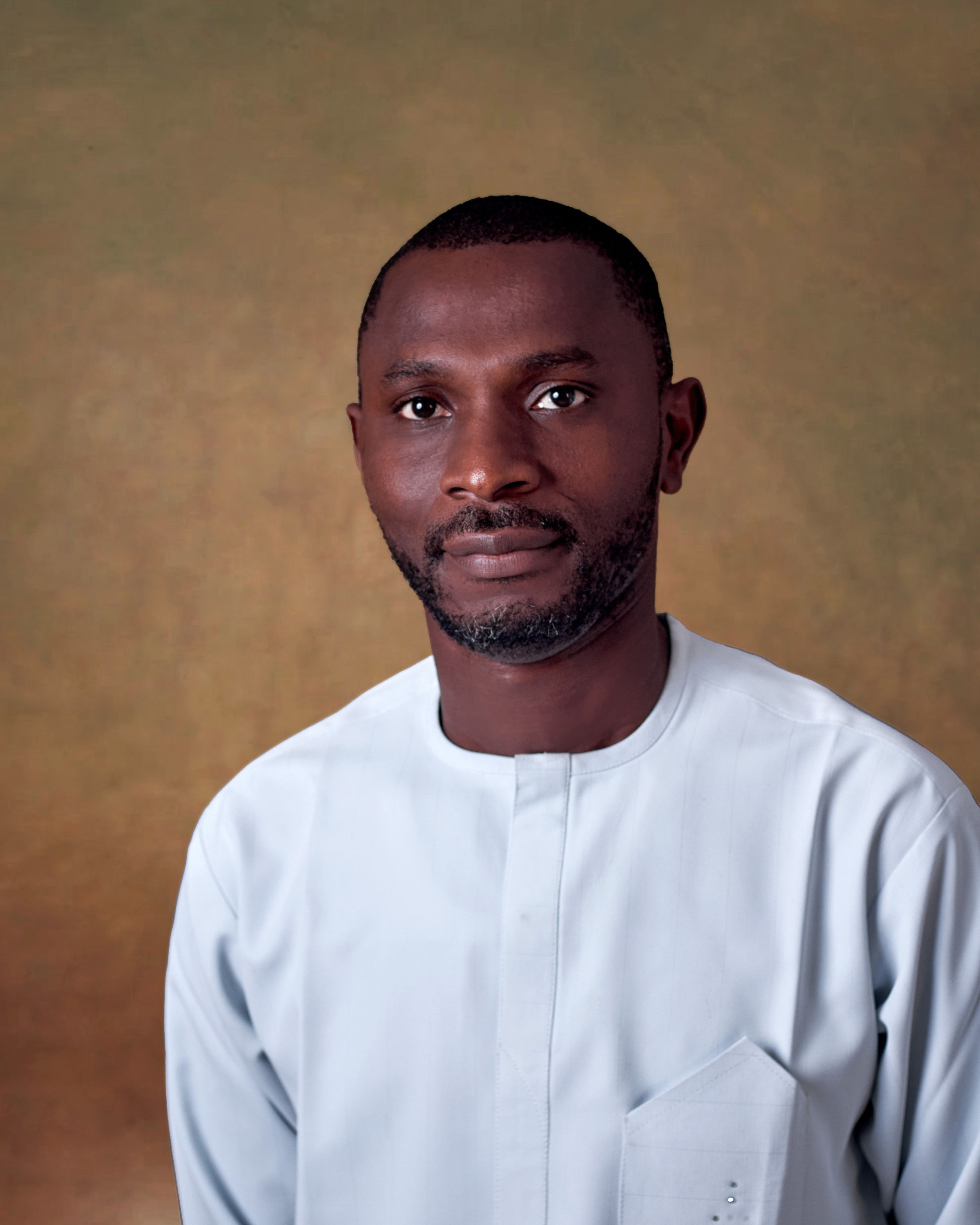 Studio portrait of a man wearing traditional white attire with a neutral background.
