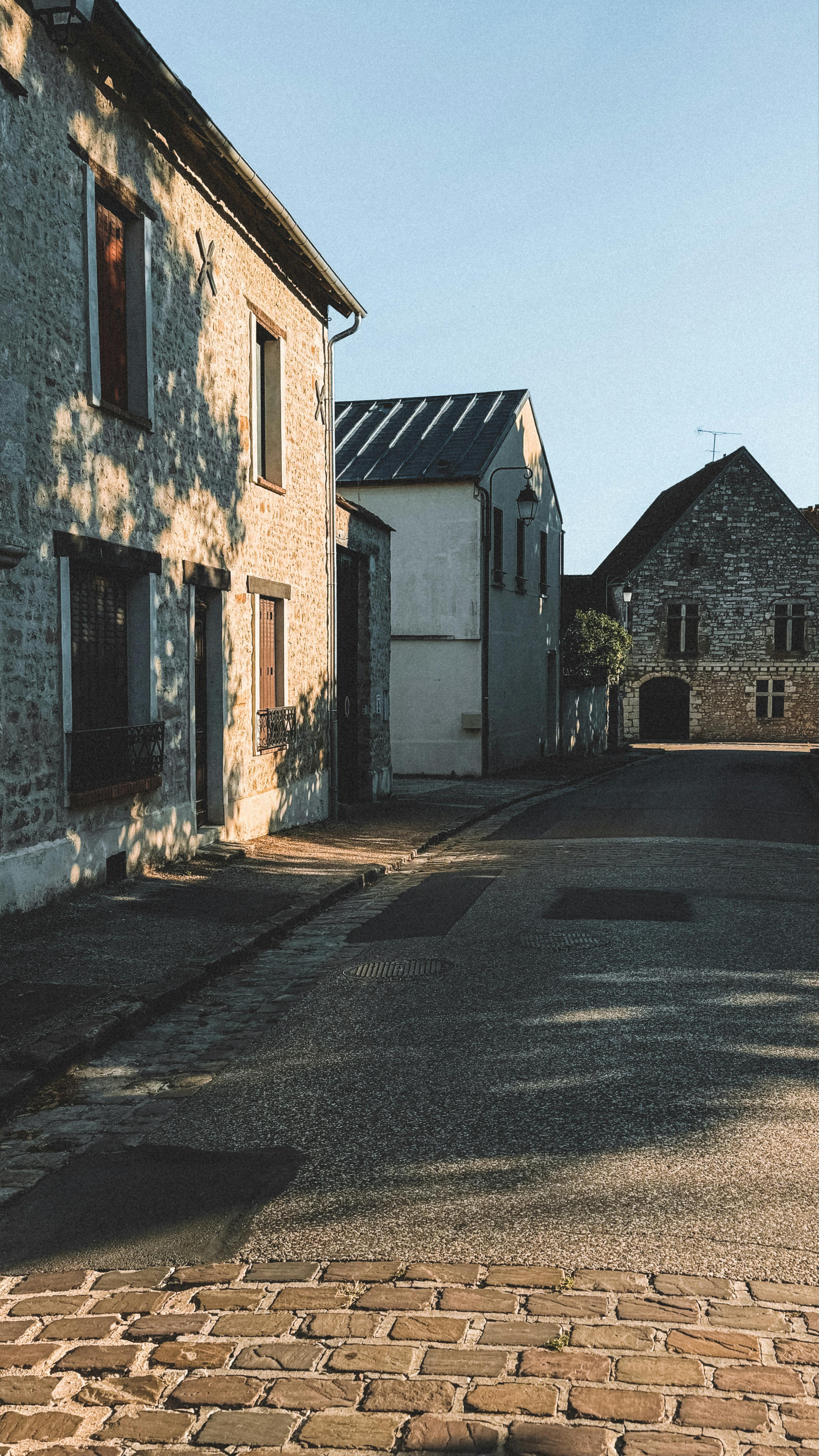 Quaint stone buildings on a quiet street in a picturesque French village during daytime.