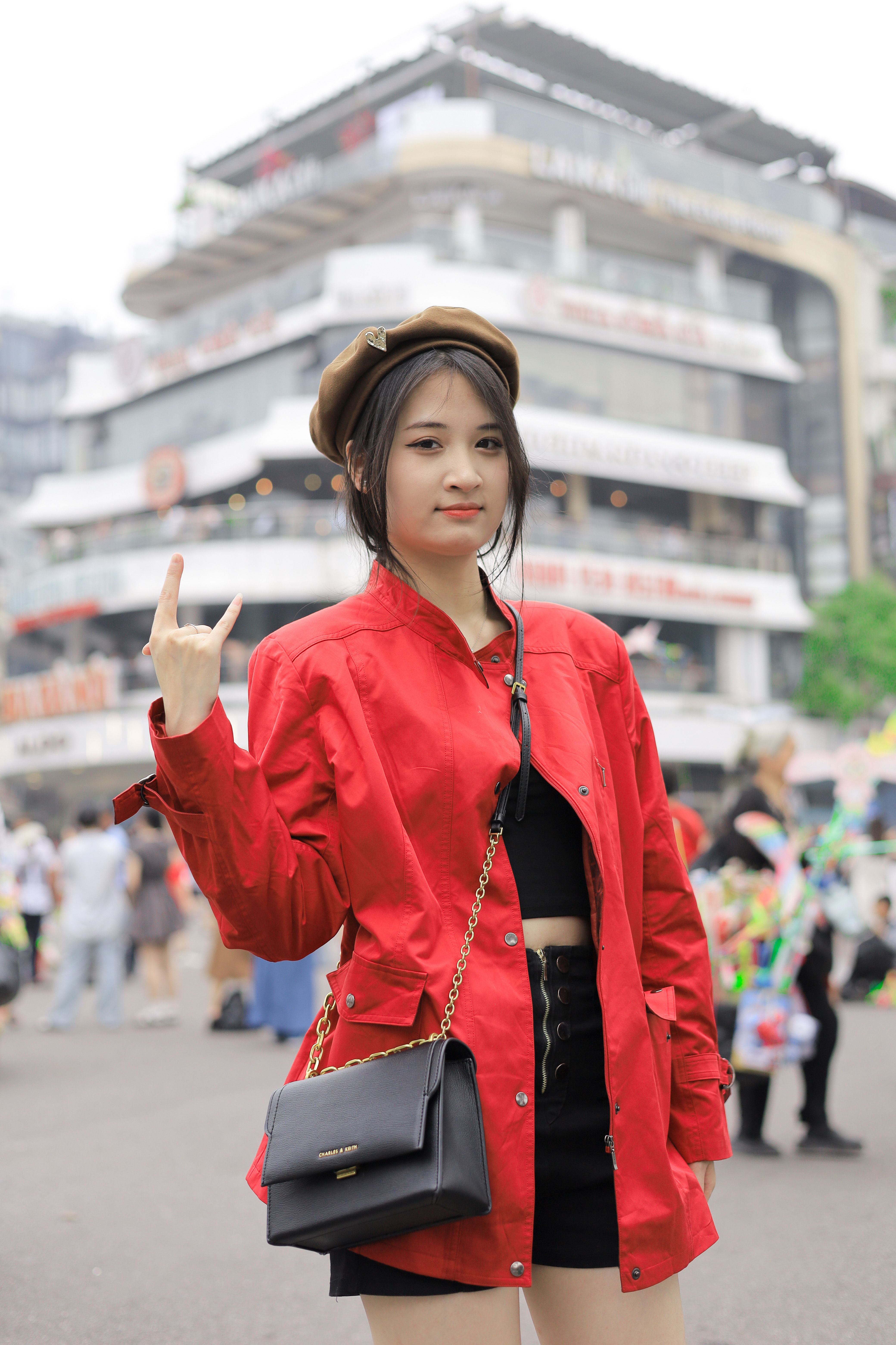Stylish young woman poses confidently in Hà Nội, Vietnam wearing a red jacket and black skirt.