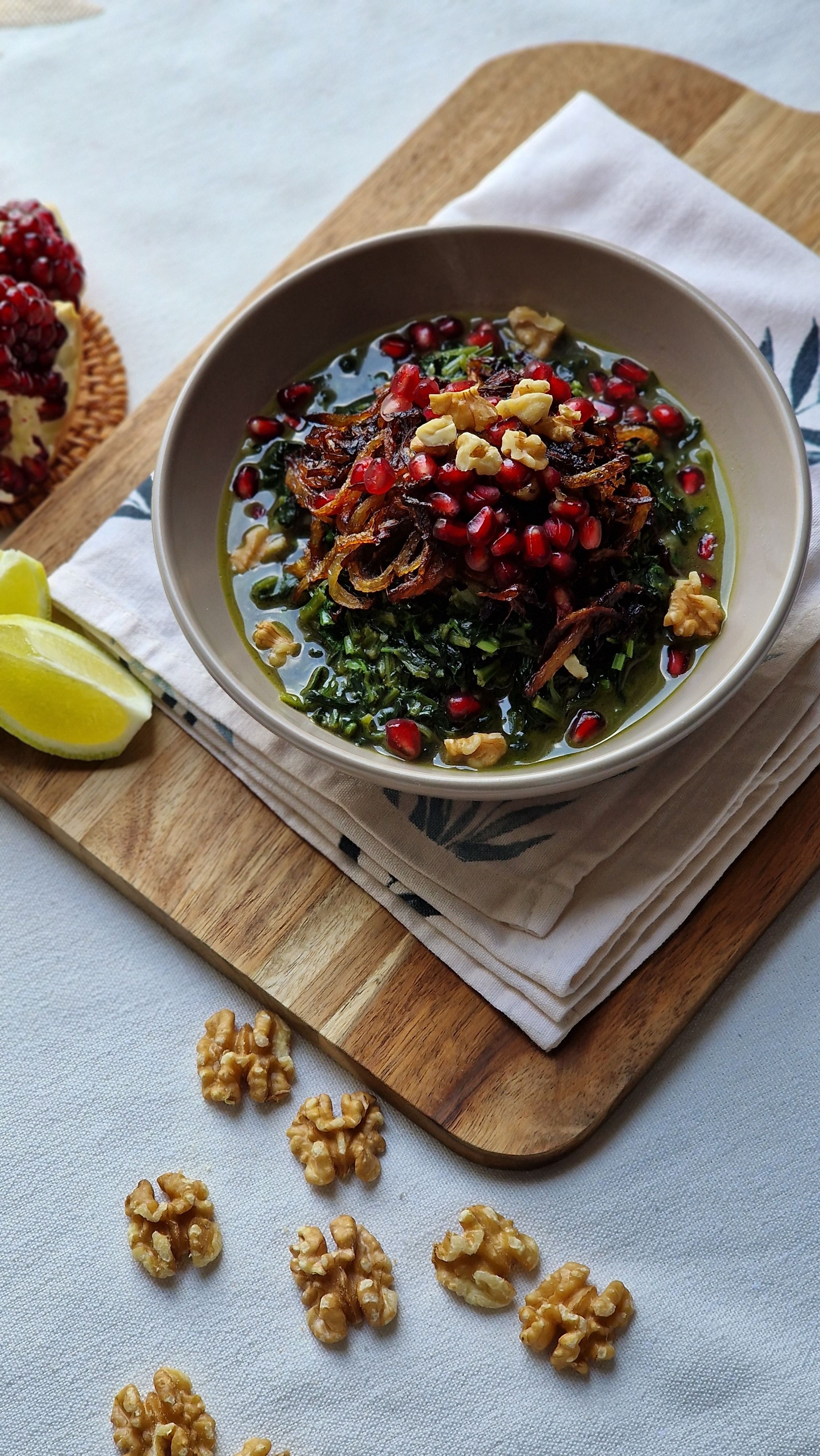 Healthy dish with walnuts, pomegranate, and herbs in a bowl, showcasing vibrant colors.