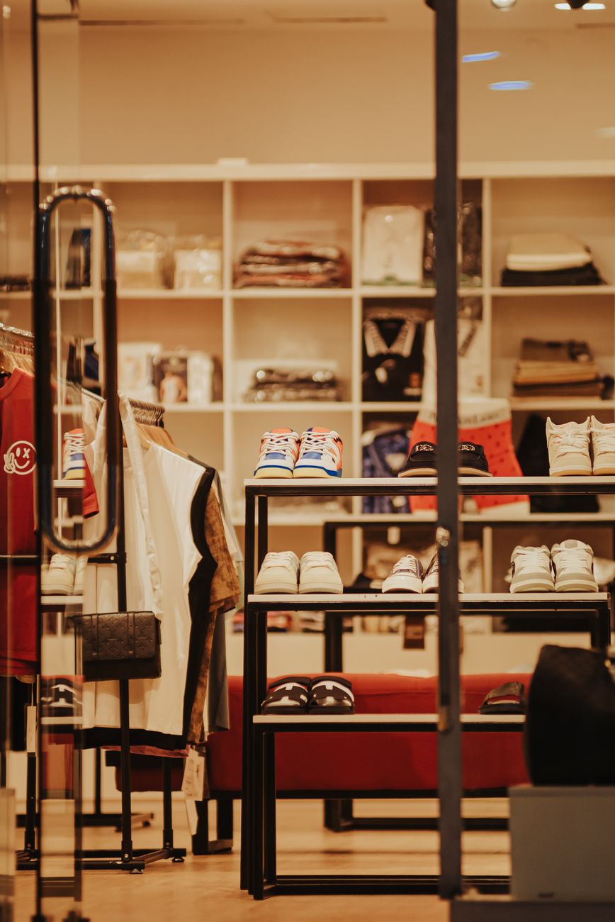 Interior of a fashionable boutique showcasing clothing, shoes, and accessories neatly arranged on shelves.