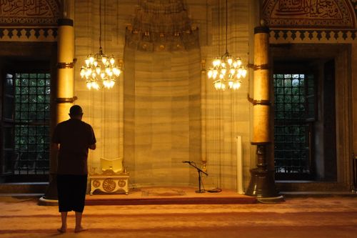 Free A man prays inside a beautifully lit, historic mosque interior in Istanbul, Turkey. Stock Photo
