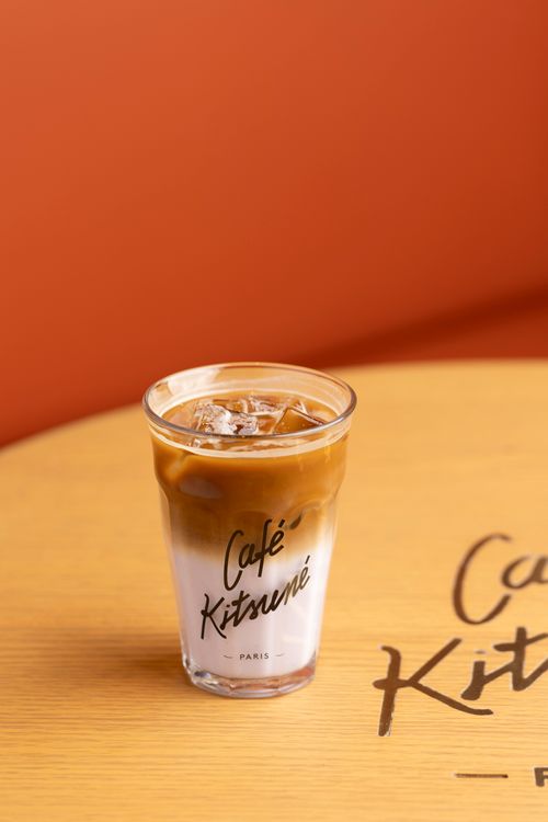 De franc Latte gelat en un got de Cafè Kitsuné sobre una taula de fusta, ambient càlid. Foto d'estoc