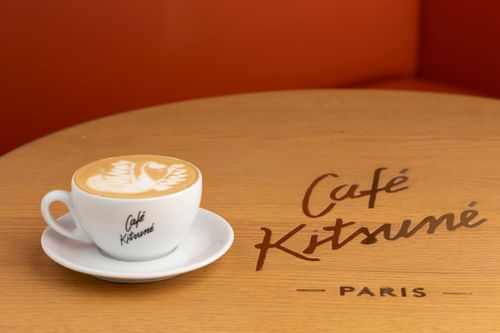 Free A cappuccino with latte art on a table at Café Kitsuné in Paris, perfect for coffee lovers. Stock Photo